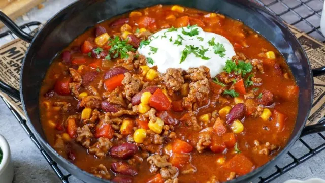 Chili con Carne mit Rinderhackfleisch, Kidneybohnen, Mais, Paprika und Tomaten in einer dunklen Schale