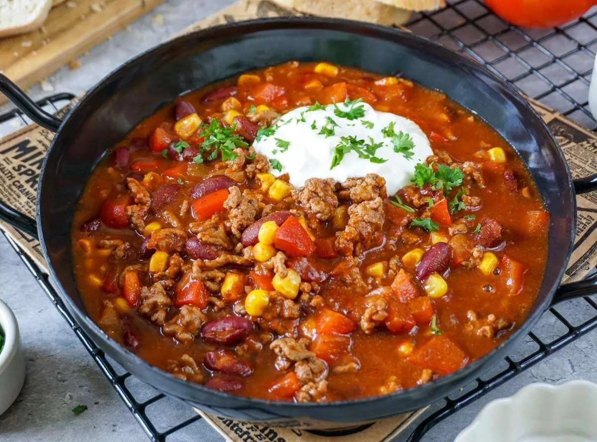 Chili con Carne mit Rinderhackfleisch, Kidneybohnen, Mais, Paprika und Tomaten in einer dunklen Schale
