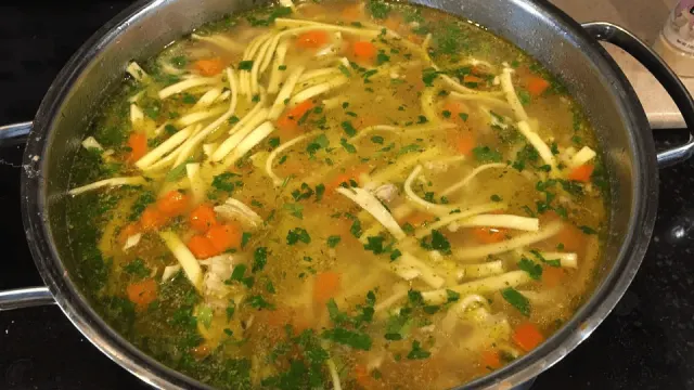 Klare Hühnernudelsuppe mit Hühnerfleisch, kleinen Nudeln und fein geschnittenem Suppengemüse
